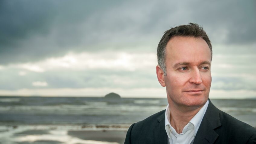 Horizontal portrait of Andrew O'Hagan with Ailsa Craig in the background. Subject to Terms and Conditions.